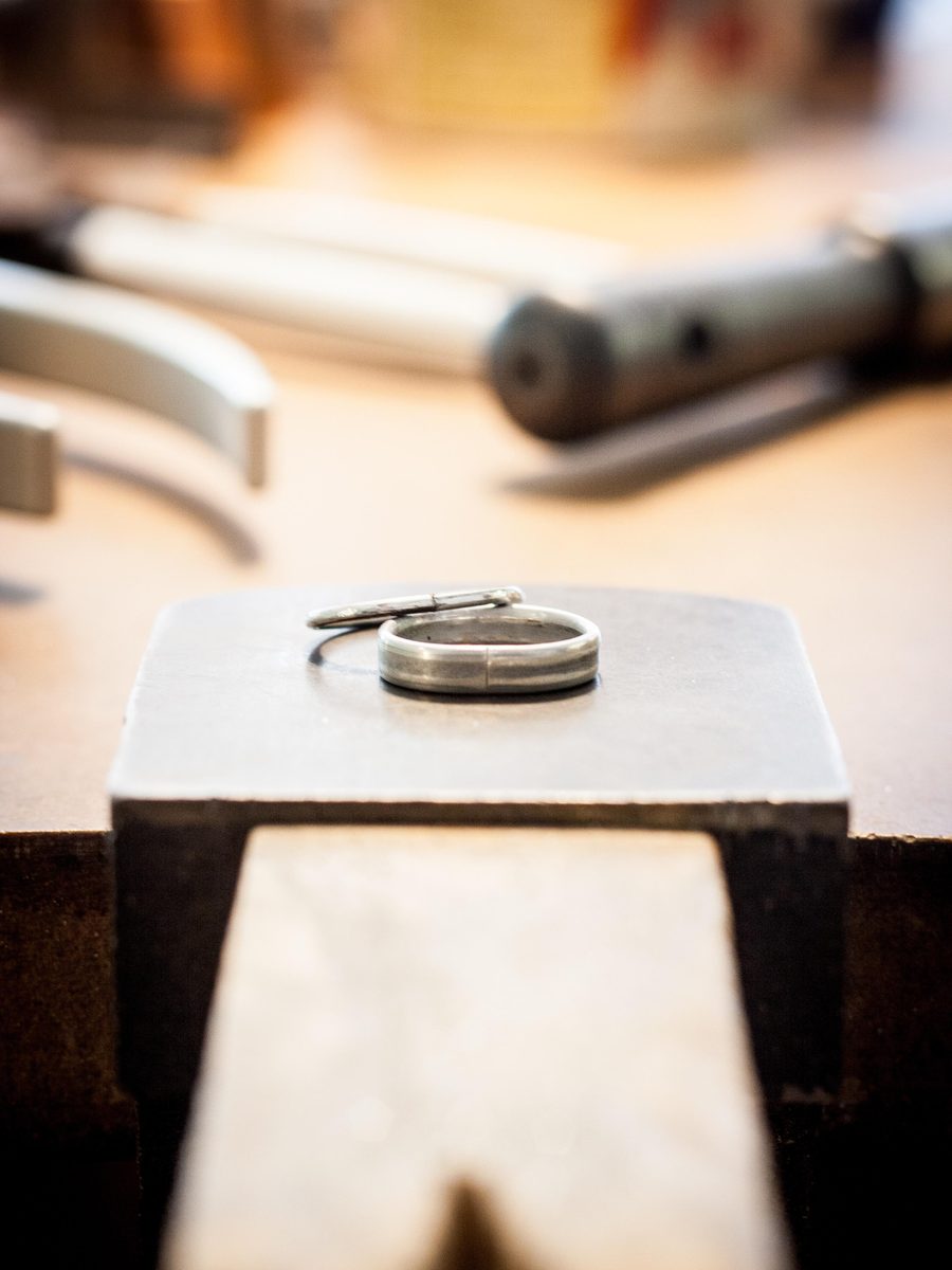 Bague posée sur le tas à sertir, outils de l'établi à l'arrière-plan
